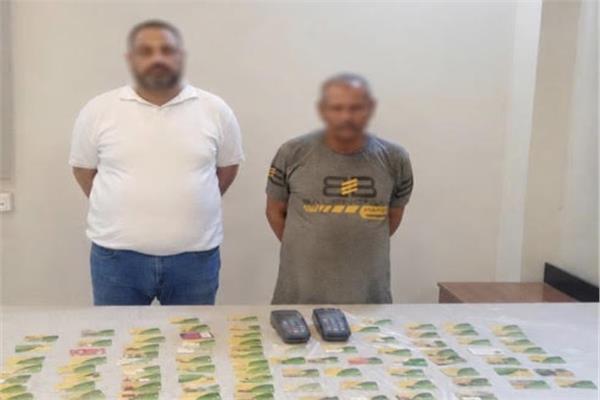المتهمان وأمامهما المضبوطات